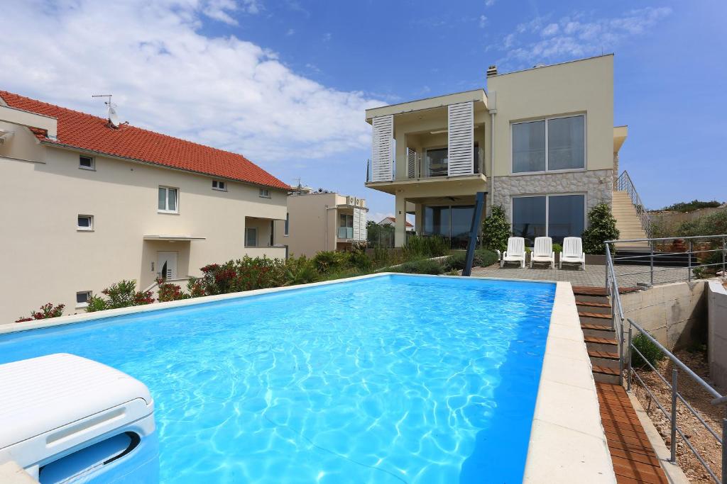 a swimming pool in front of a house at Villa Summer Dreams Apartments in Murter