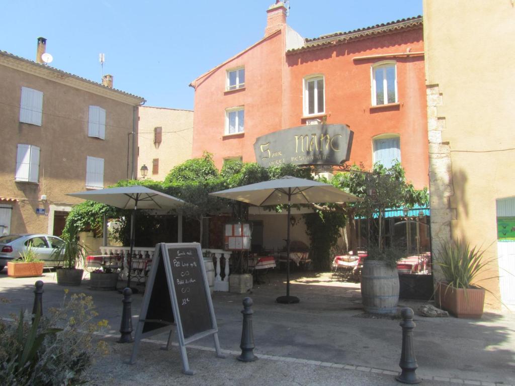 um restaurante com guarda-sóis em frente a um edifício em Hôtel Restaurant le Saint Marc em Aups