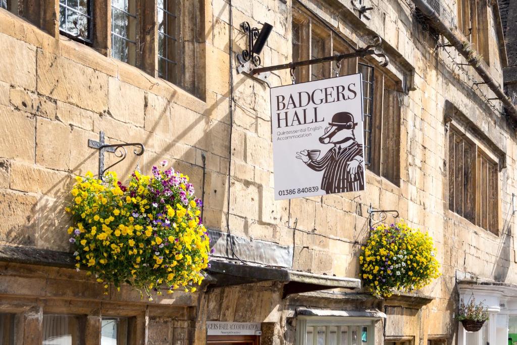 a building with flowers and a sign on the side of it at Badgers Hall in Chipping Campden