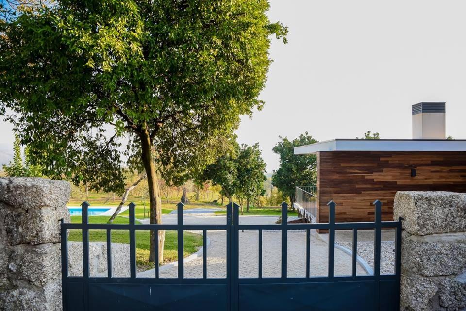 Ein schwarzer Zaun mit einem Baum und einem Gebäude in der Unterkunft Regada House in Vieira do Minho