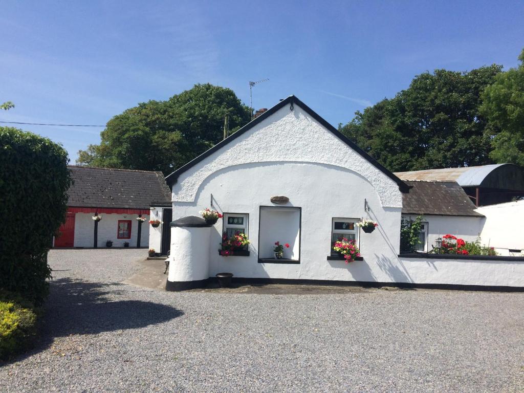 a white building with flower boxes on the windows at Shannon Breeze Cottage in Ballycrossaun
