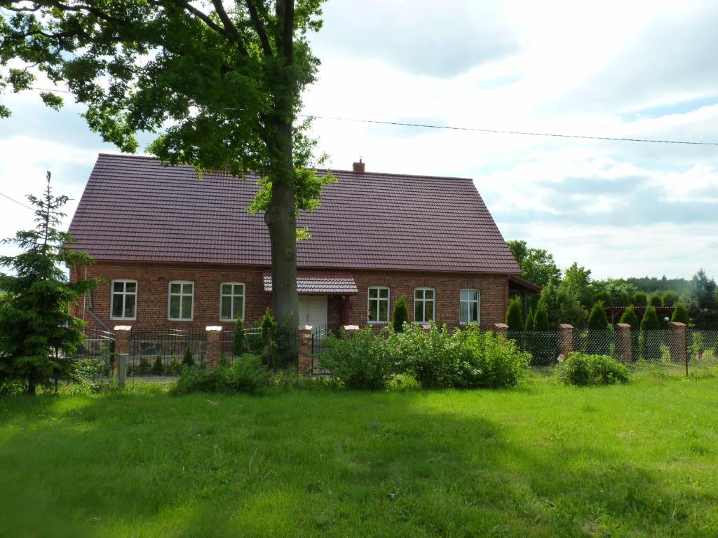 uma casa vermelha com uma árvore no quintal em Sloneczna Weranda em Wydminy