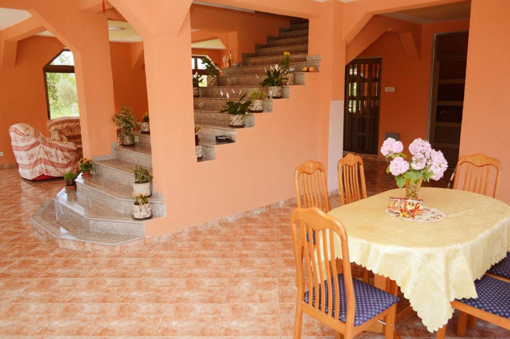 uma sala de jantar com mesa, cadeiras e escadas em Guest House Lukac em Bar