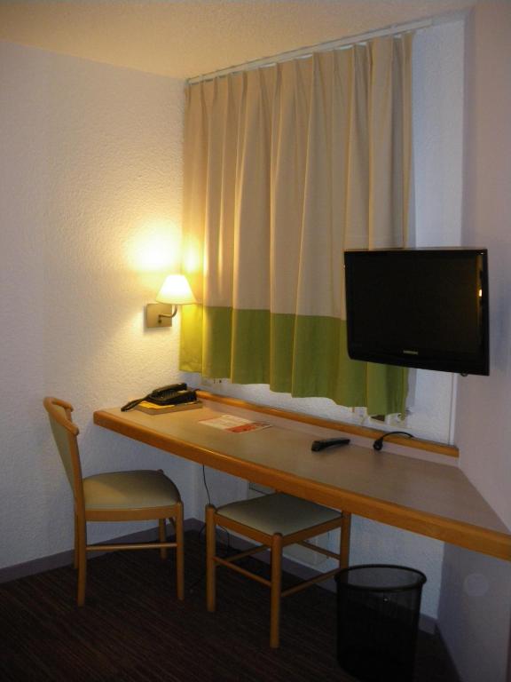 a room with a desk with a monitor and a chair at Logis Hôtel Le Relais du Moulin in Valençay