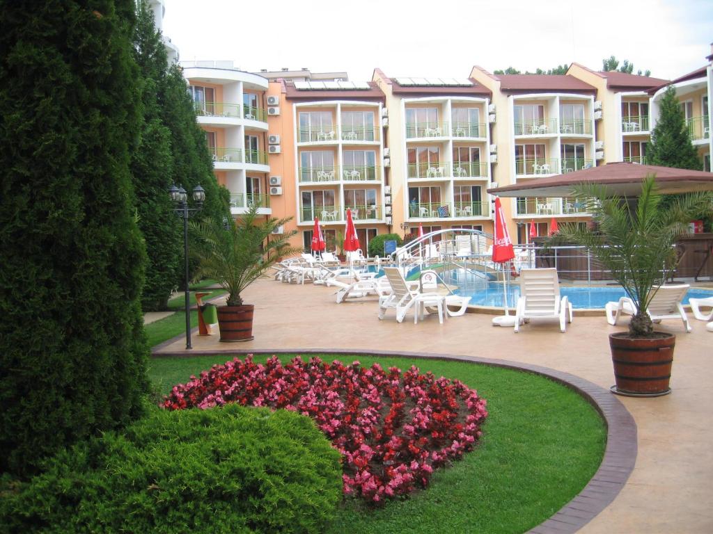 a hotel with a flower garden in front of a pool at Sun City Hotel in Sunny Beach