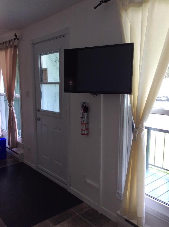 a flat screen tv hanging on a wall next to a door at Camping Le 4 Chemins in LʼAnse-Saint-Jean