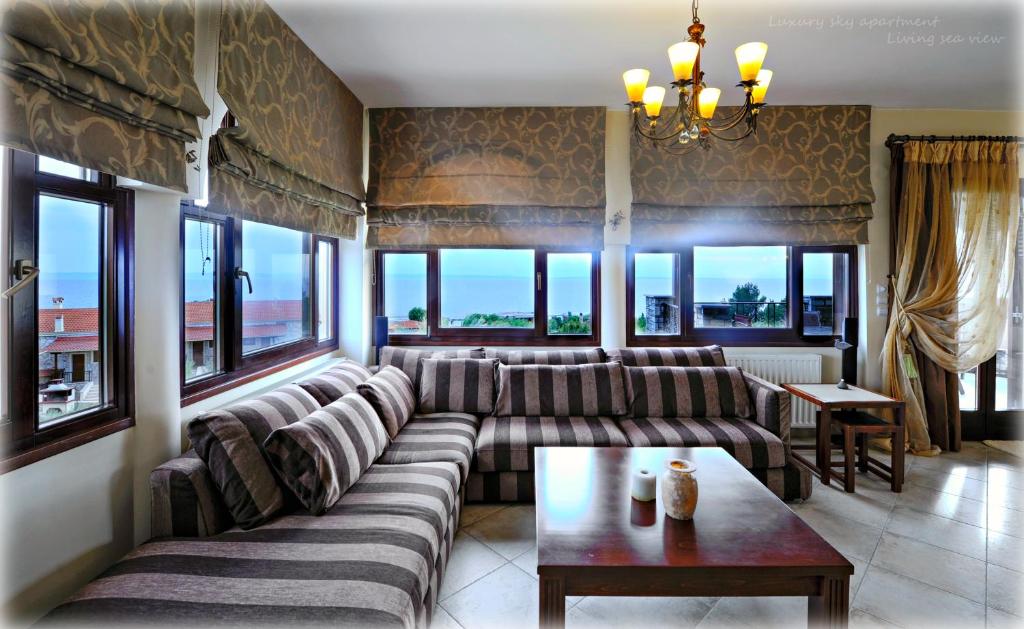 a living room with a couch and a table and windows at Castri Deluxe Sky Apartment in Nikiti