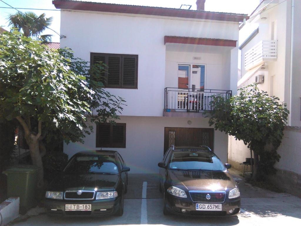 dos autos estacionados frente a una casa en Apartments Dana, en Zadar