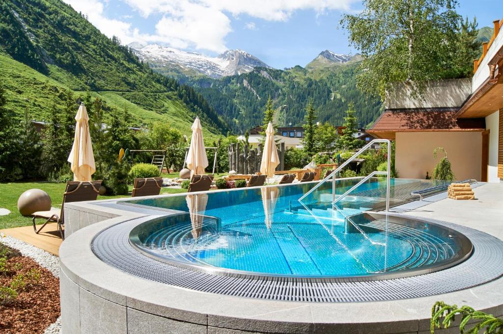 a swimming pool in a resort with mountains in the background at Hotel Alpenhof in Tux