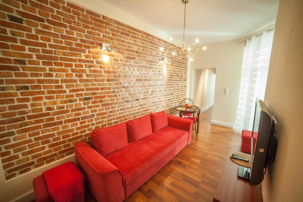 a living room with a red couch against a brick wall at My place in Poznan in Poznań