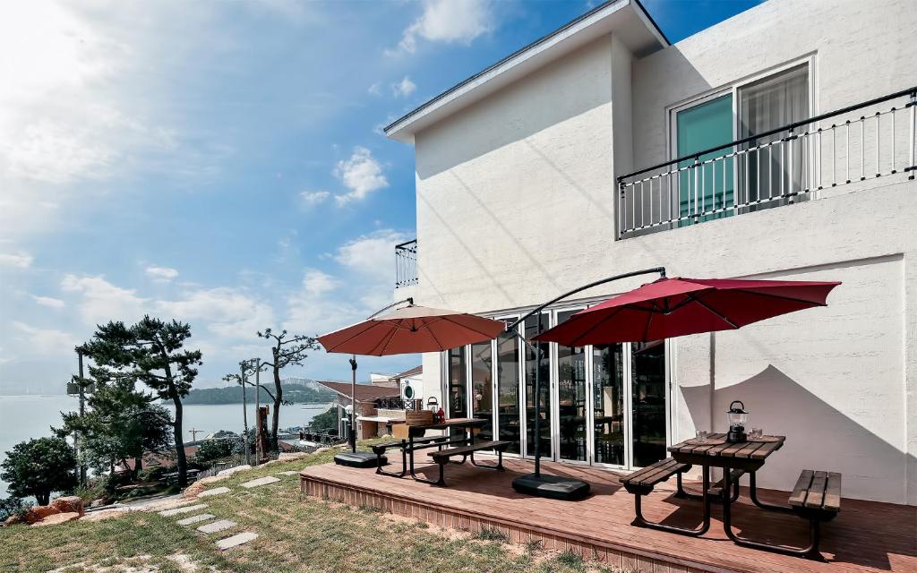 patio z dwoma stołami i parasolami przed budynkiem w obiekcie Yeosu Blooming Pension w mieście Yeosu