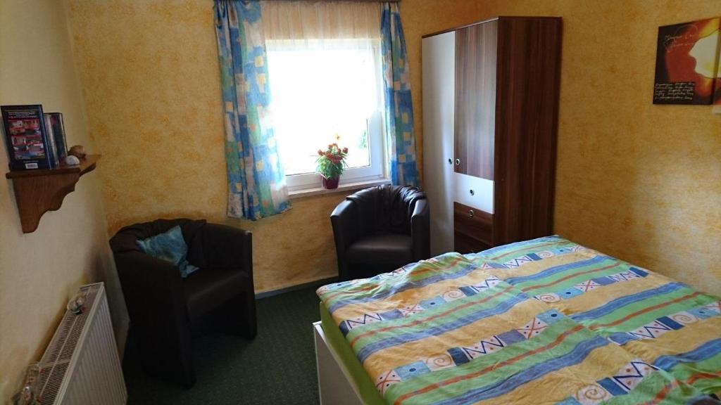 a bedroom with a bed and two chairs and a window at Bungalow in strandnähe in Mönkebude