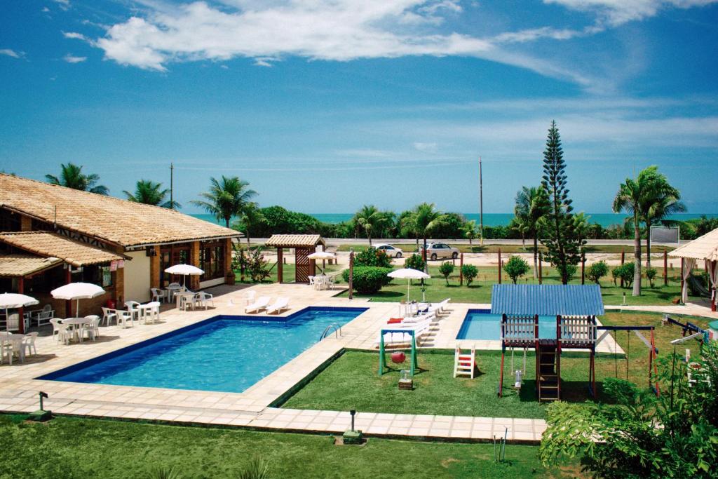 un complexe doté d'une piscine avec des chaises longues et des parasols dans l'établissement Sueds Cabralia, à Santa Cruz Cabrália