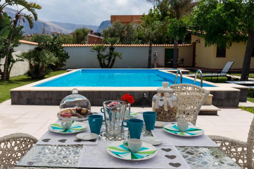 einen Tisch mit Speisen neben einem Pool in der Unterkunft Vero Sicily - Villa San Giorgio in Cinisi