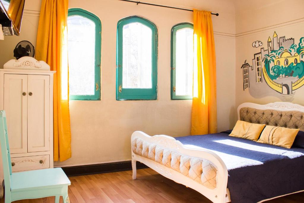 a bedroom with a bed and four windows at Hostal Forestal in Santiago