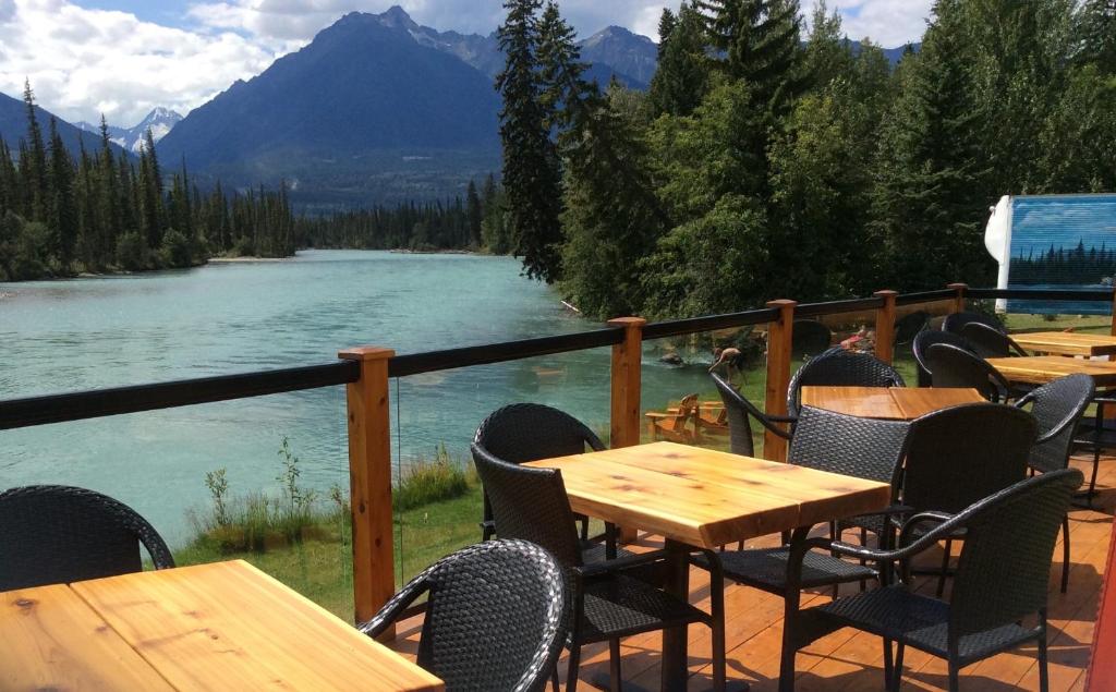 een patio met tafels en stoelen naast een rivier bij Tete Jaune Lodge in Tete Jaune Cache