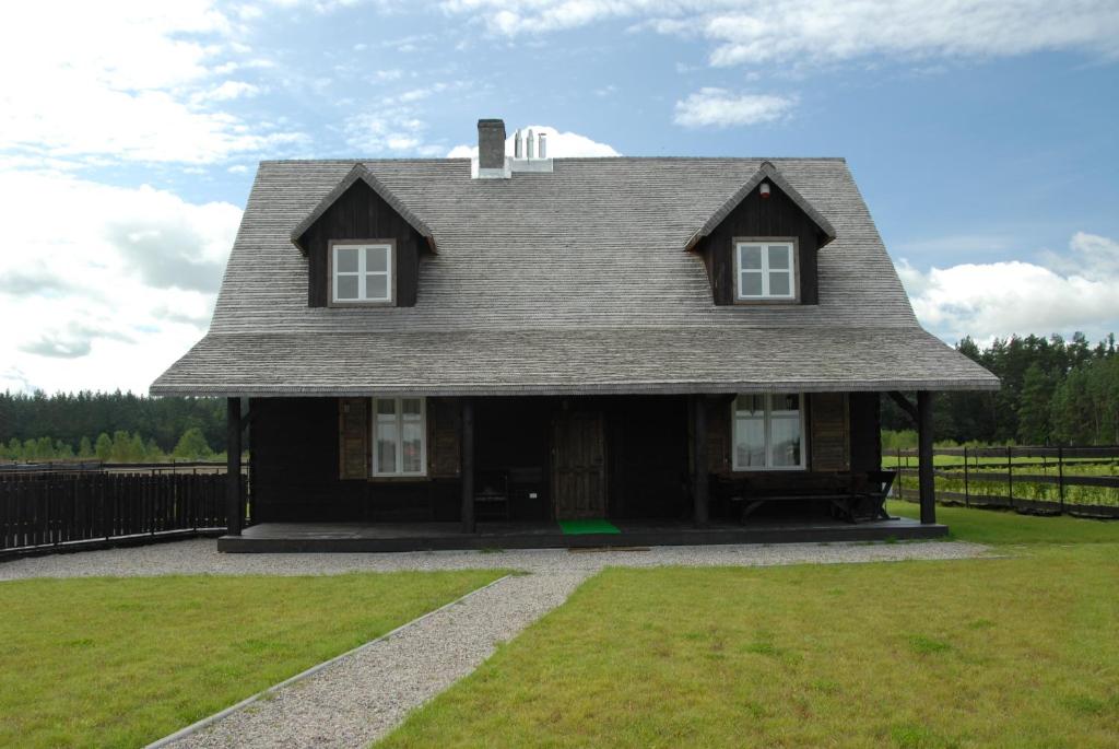 a house with a gambrel roof on top of a yard at Osada Rydzewo in Rydzewo