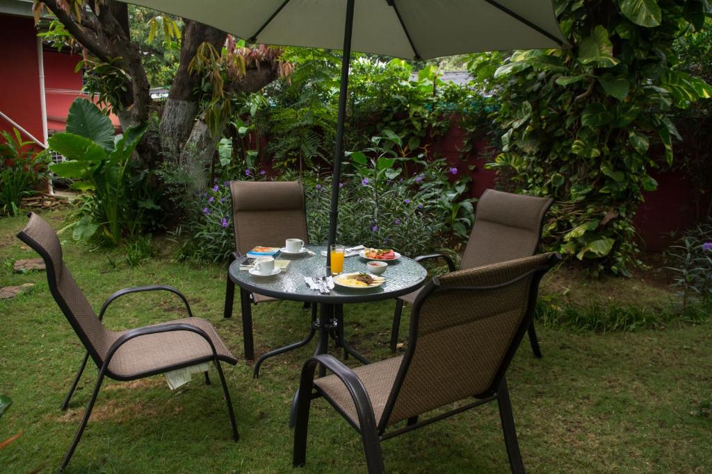 a table with chairs and an umbrella with food on it at Hostal Casa Los Espinoza in Managua