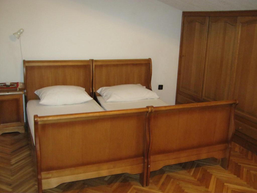 a wooden bed with two pillows in a room at Apartments Nestor in Tribunj