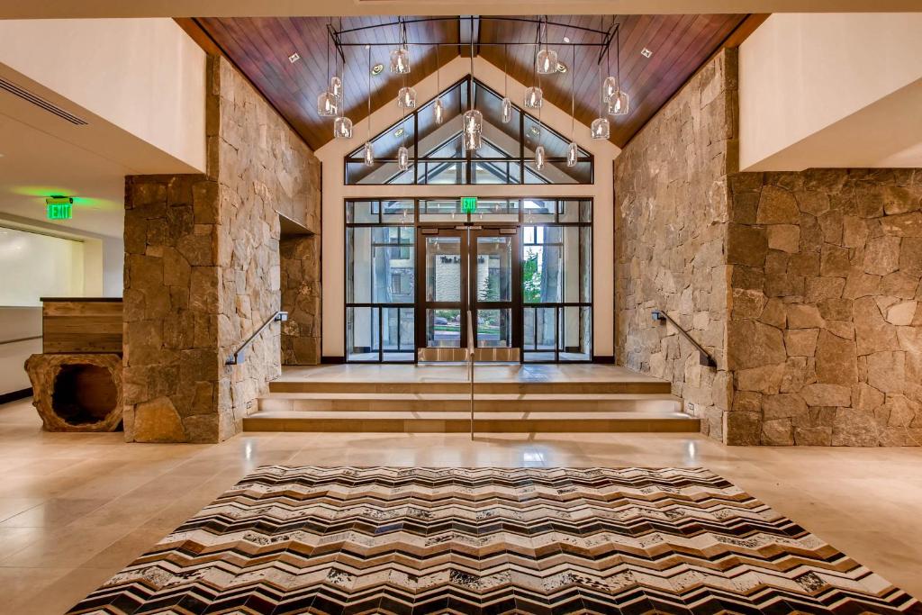 a lobby with stairs and a stone wall at The Lion Vail in Vail