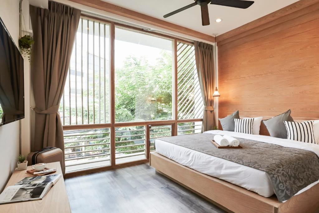 a bedroom with a bed and a large window at Vann Bangkok Boutique House in Bangkok