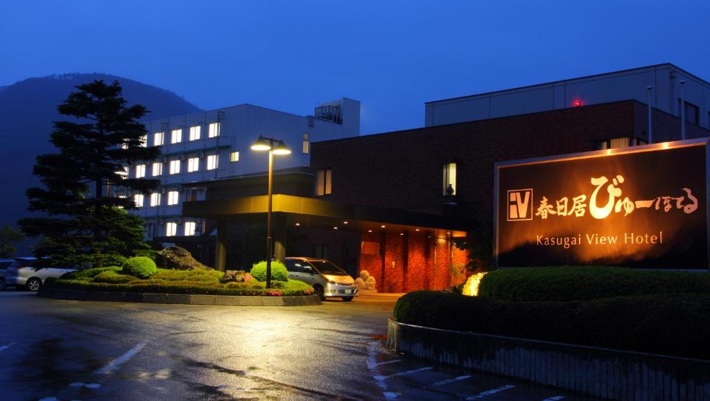 um parque de estacionamento em frente a um edifício à noite em Kasugai View Hotel em Fuefuki