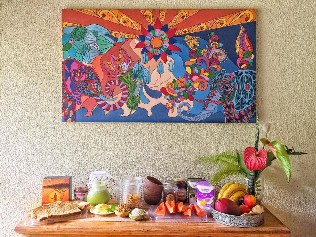 a table with food and a painting on the wall at Espaço CurAmar - Praia de Itamambuca in Ubatuba