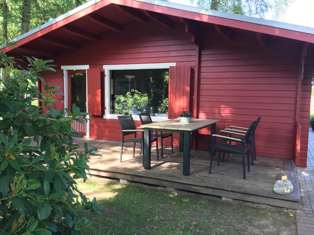 a red house with a table and chairs on a deck at Huck’s Ferienhäuser in Borstel