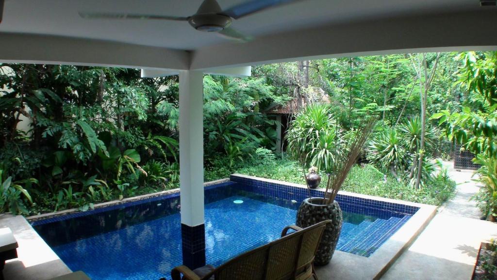 uma vista para uma piscina a partir do alpendre de uma casa em Enkosa 4-Bedroom Wooden Luxury House em Siem Reap