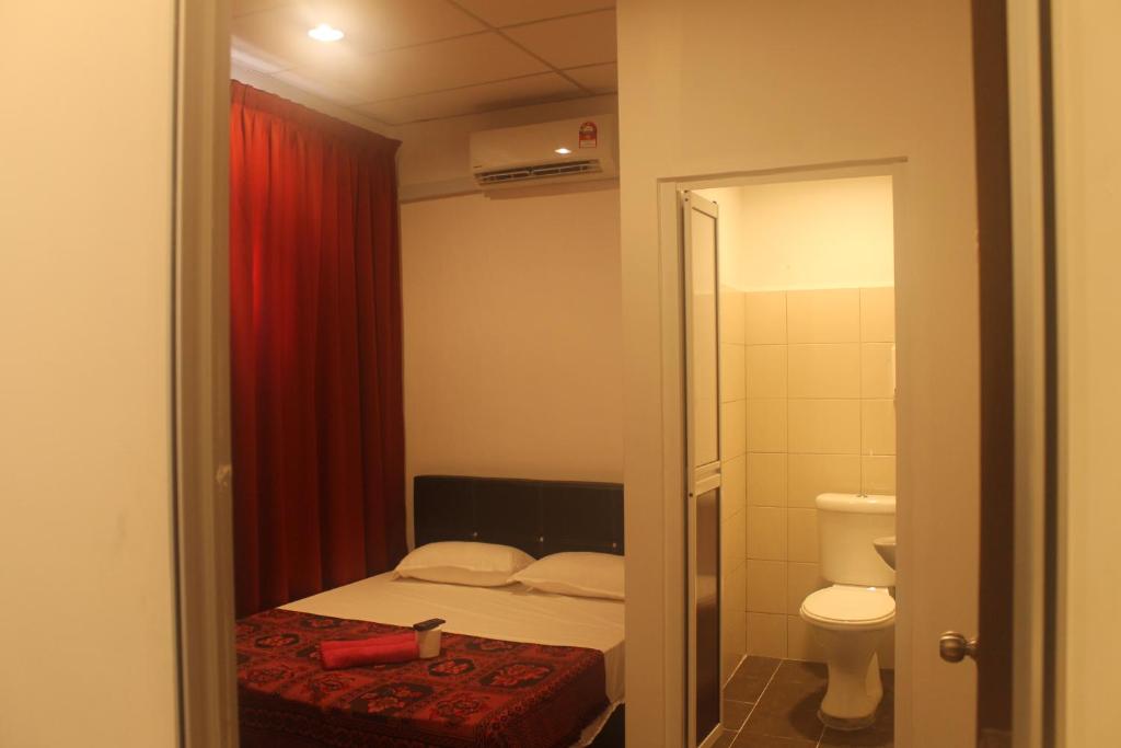 a small bedroom with a bed and a toilet at Georgetown Heritage Motel in George Town