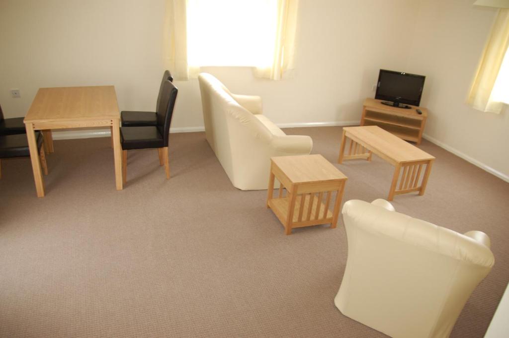 a living room with chairs and a table and a tv at Warrens Village Motel and Self Catering in Clevedon