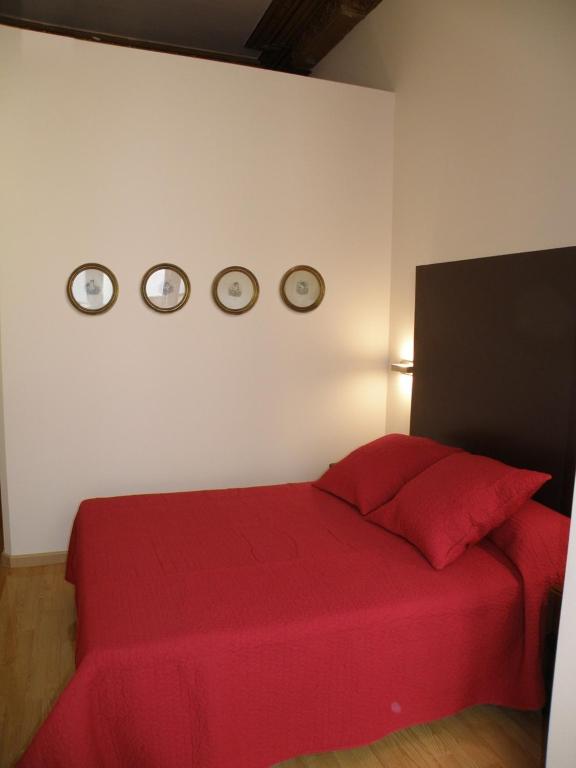 a bedroom with a red bed and three clocks on the wall at Center Gran Via in Barcelona