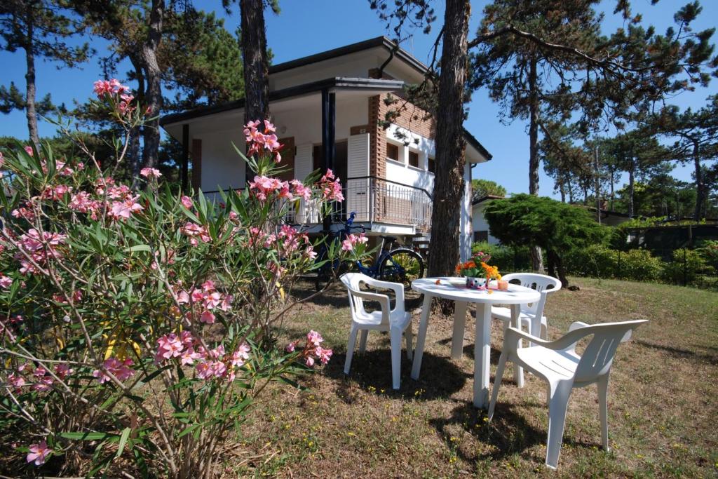 une table et des chaises devant une maison fleurie dans l'établissement Villaggio Alex, à Lignano Sabbiadoro