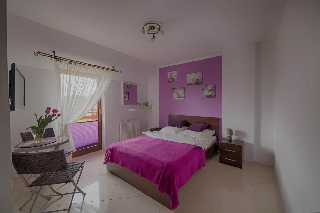 ヤロスワビエツにある4 strony świataのベッドルーム(紫色のベッド1台、テーブル、椅子付)