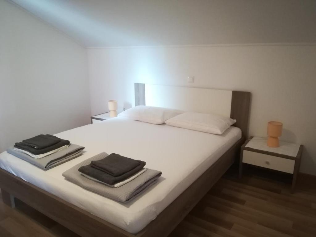 a bedroom with a white bed with towels on it at Apartments Nikola Caska in Novalja