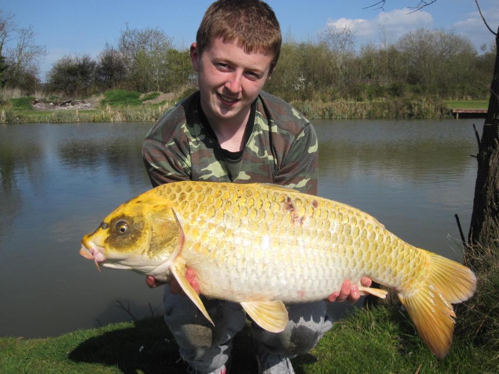 a man holding a large fish in front of a pond at Warrens Village Motel and Self Catering in Clevedon