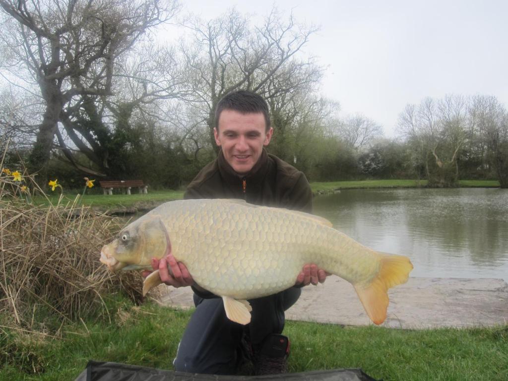 a man holding a fish in front of a pond at Warrens Village Motel and Self Catering in Clevedon
