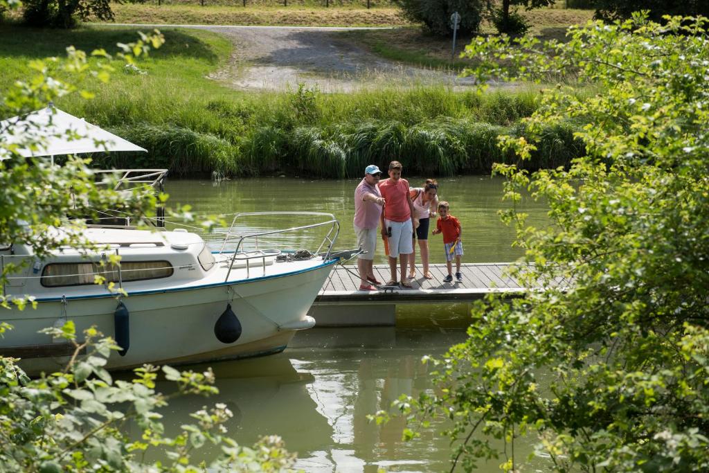 a group of people standing on a dock next to a boat at Camping Du Port De Plaisance in Péronne