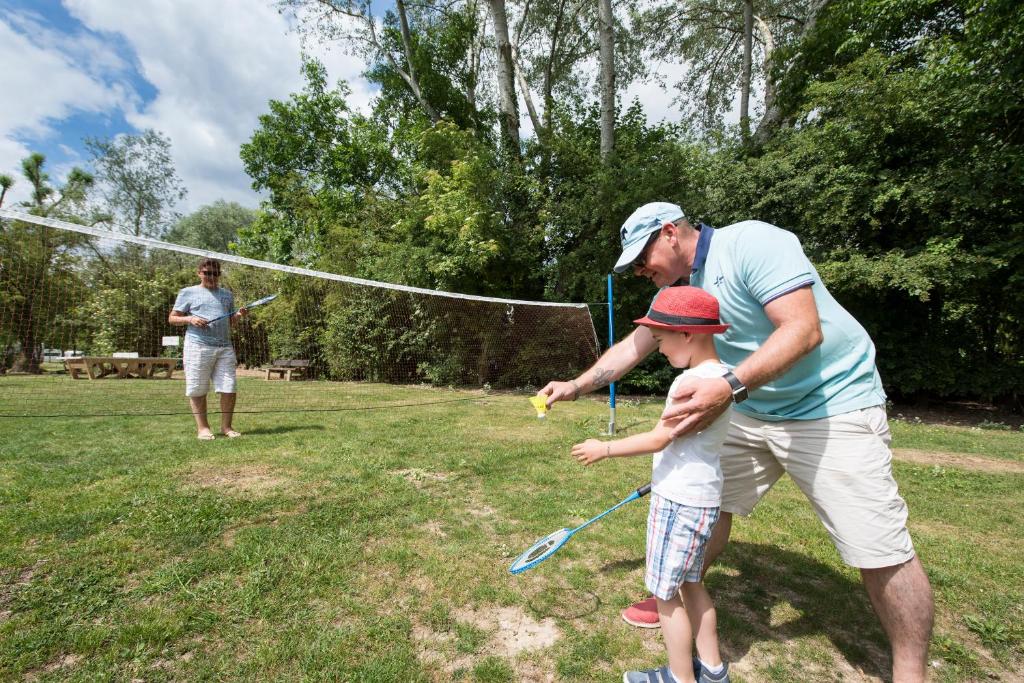a man and a child playing with a water hose at Camping Du Port De Plaisance in Péronne