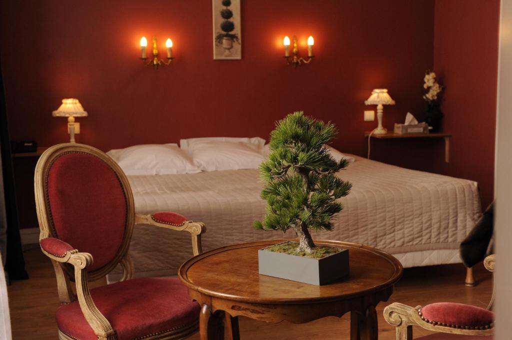 a bedroom with a bed and a table with a tree on it at Hôtel De La Cathédrale in Rouen
