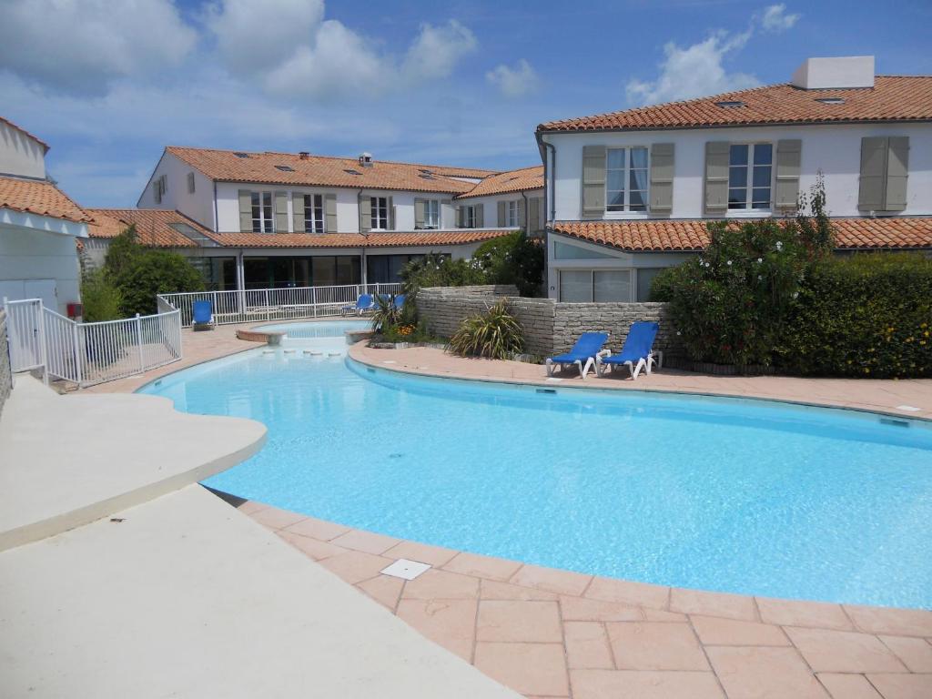 a large swimming pool with two chairs and a house at Duplex 6-7 p Résidence proche plage in La Couarde-sur-Mer