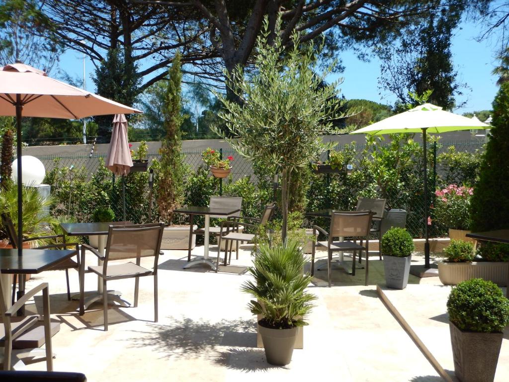 a patio with tables and chairs and umbrellas at Hotel Miramar- Cap d'Antibes - La Garoupe plage in Antibes