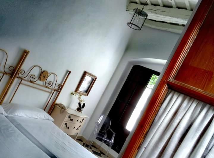 a bedroom with a bed and a window and a mirror at Posada de Palacio in Sanlúcar de Barrameda