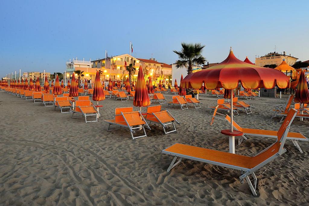 una fila de sillas y sombrillas en una playa en Hotel & Residence Cavalluccio Marino, en Rímini