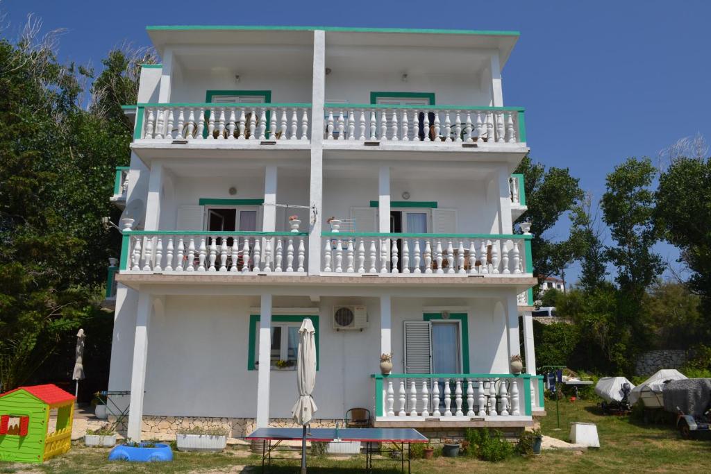 a white building with a balcony and a table at Apartmani Jenny i Tania in Lopar