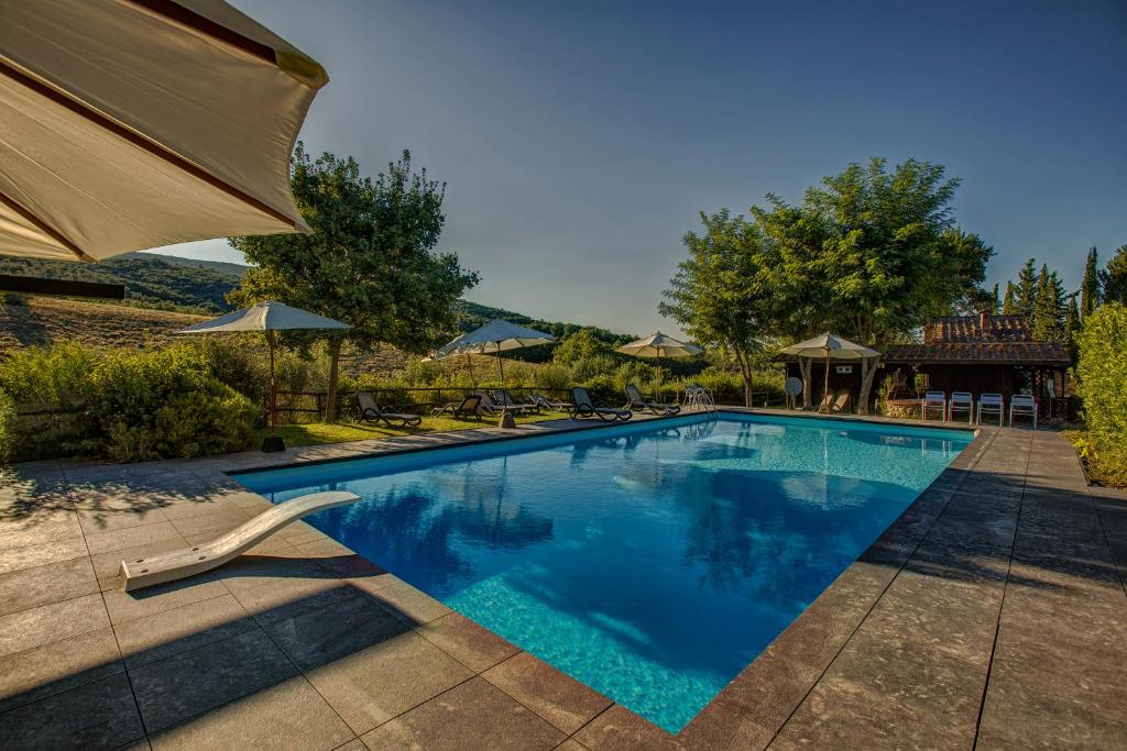 a swimming pool with chairs and an umbrella at Casanova di Pescille in San Gimignano