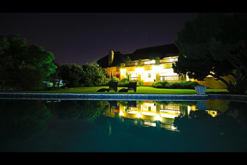 a house lit up at night with a swimming pool at Blue Hills Lodge in Midrand