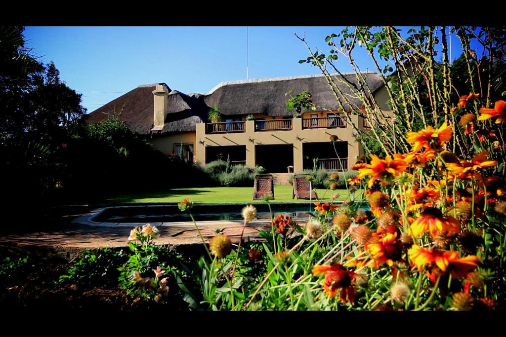 a house with a yard with flowers in front of it at Blue Hills Lodge in Midrand