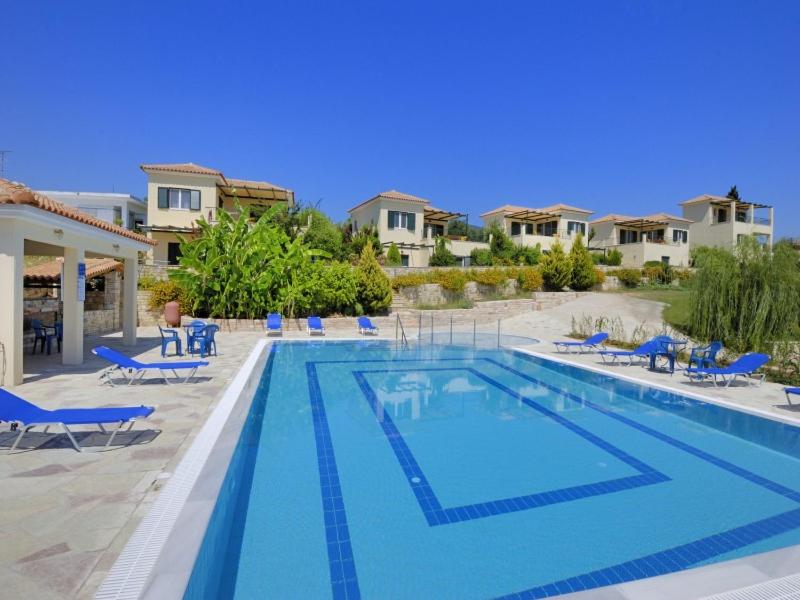 una gran piscina con sillas azules y apartamentos en condominio en Il Villaggio, en Chrani