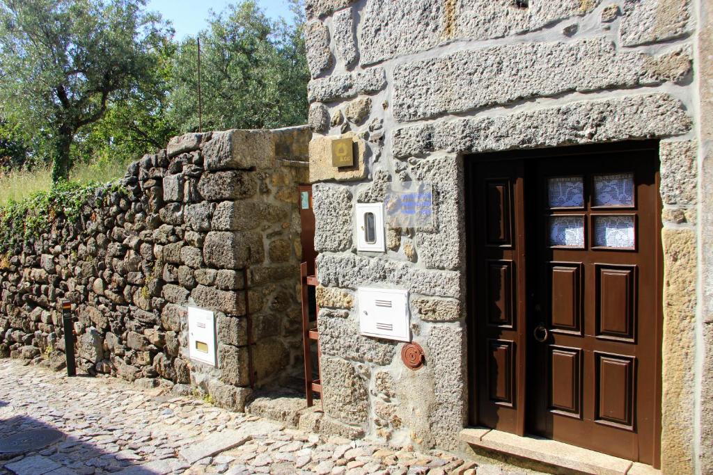 a stone building with a door and a stone wall at Casa Pissarra in Linhares